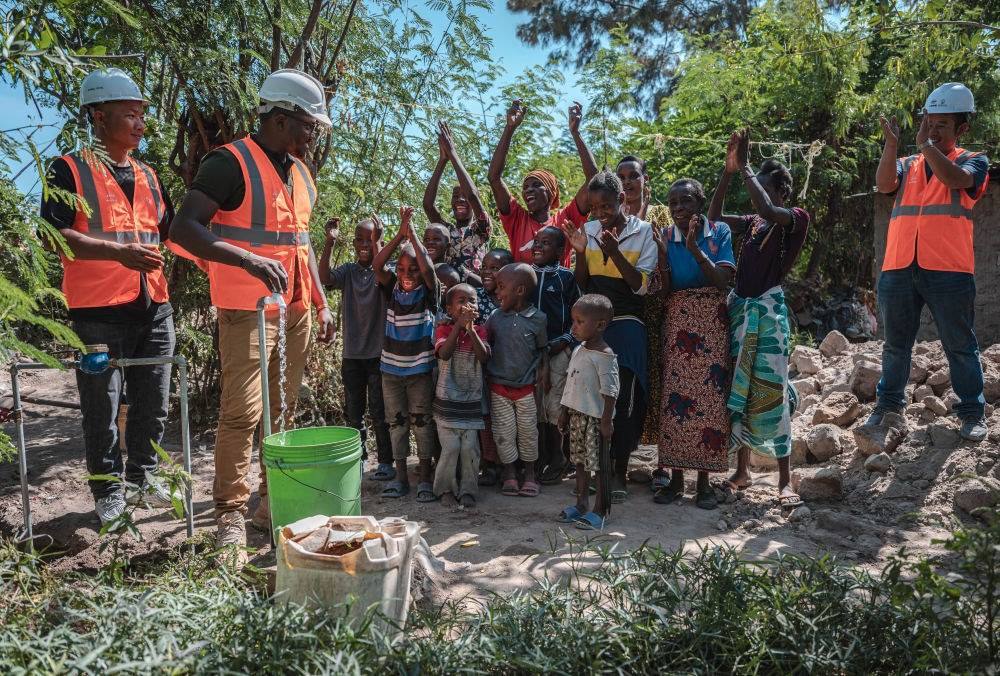 2023年6月13日，在坦桑尼亞姆萬扎省米松圭，工作人員接通水管后贏得當(dāng)?shù)鼐用窆恼茪g呼。新華社記者 王冠森 攝