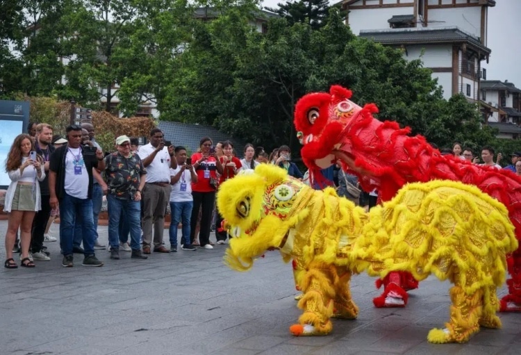 2024“一帶一路”媒體合作論壇聯(lián)合采訪調(diào)研行成員在樂(lè)山蘇稽古鎮(zhèn)觀看非遺舞獅表演。本報(bào)記者 伊霄攝