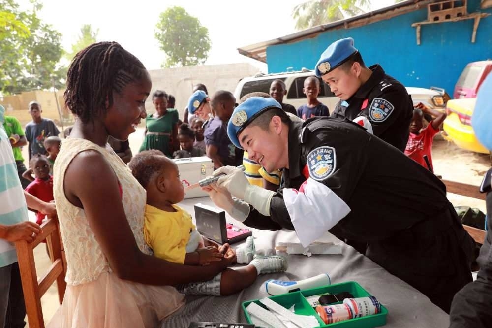 2017年12月28日，在利比里亞蒙羅維亞，中國維和警察防暴隊醫(yī)療人員為兒童做口腔檢查。