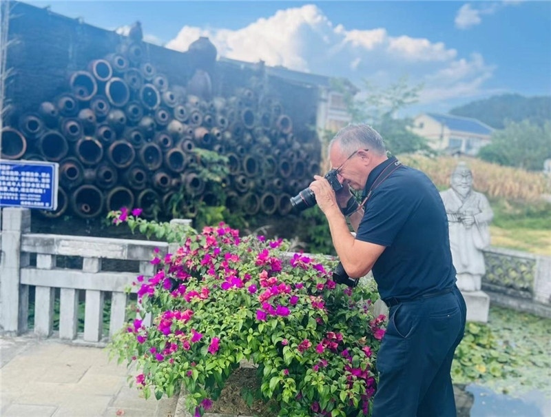 遠處黔北民居錯落有致，近處一只黑色的蝴蝶穿梭于粉紫色三角梅花叢間隙，與俄羅斯“大歐亞”總編輯弗拉基米爾·別列日內赫的鏡頭玩起了捉迷藏，“你追我逃，不亦樂乎”。（張亞欣攝）