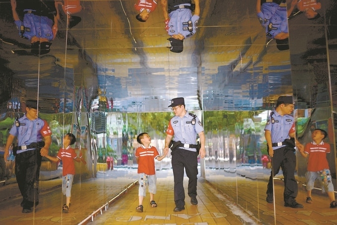 ?7月16日，重慶市公安局江北區(qū)分局一名民警在巡邏途中遇到一個獨自玩耍的小男孩，民警將其送回家。王洪平攝