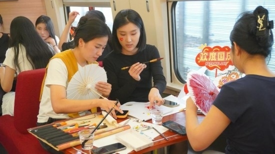 10月1日，旅客們在G1634次列車上給油紙傘作畫。新華社記者周義 攝