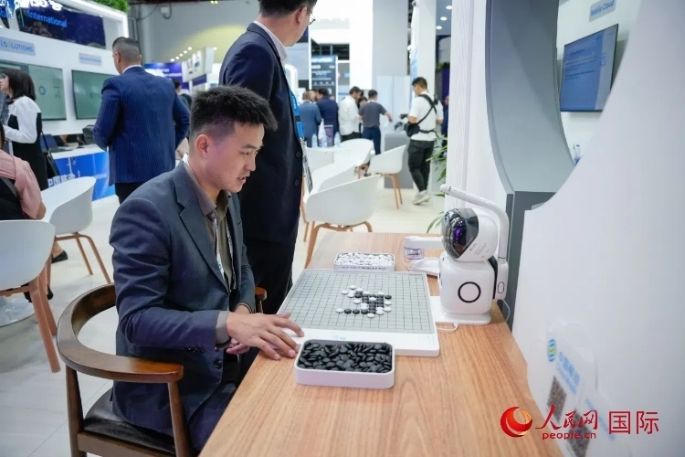 觀眾在中國移動(dòng)國際有限公司展臺體驗(yàn)智慧圍棋機(jī)器人。人民網(wǎng) 塔里克·易卜拉欣攝