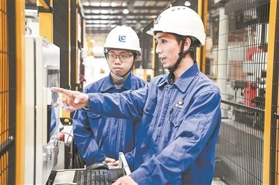 在廣西柳工機(jī)械股份有限公司生產(chǎn)車間內(nèi)，一名高級(jí)技師（右）給徒弟講解數(shù)控設(shè)備操作細(xì)節(jié)。新華社記者 曹祎銘攝