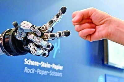 在德國漢諾威工博會上，參觀者與一款智能機器人進行“石頭剪子布”游戲。新華社發(fā)