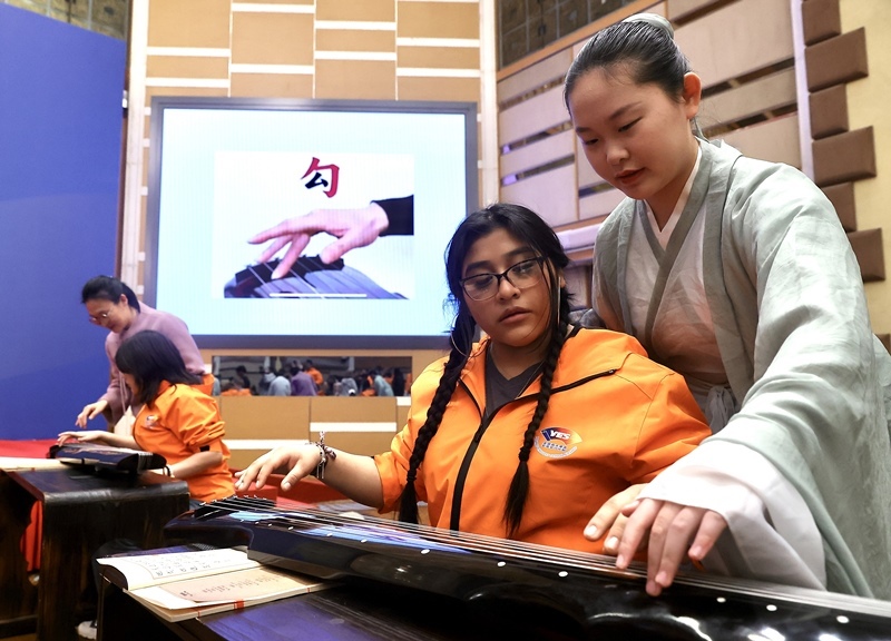 2024年3月20日，美國華盛頓州中學(xué)生代表團北京大學(xué)交流活動在北京大學(xué)英杰交流中心舉行。圖為來自華盛頓州的中學(xué)生體驗古琴。