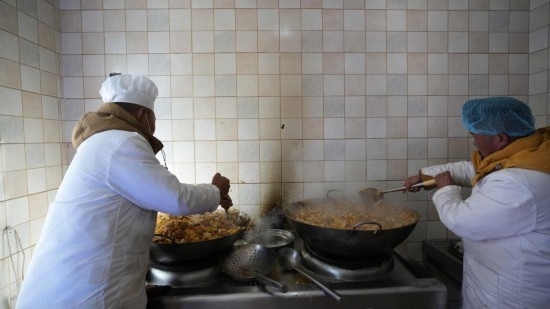 1月14日，服務(wù)隊(duì)的兩名廚師正在為村民們做午飯。新華社記者 邱星翔 攝