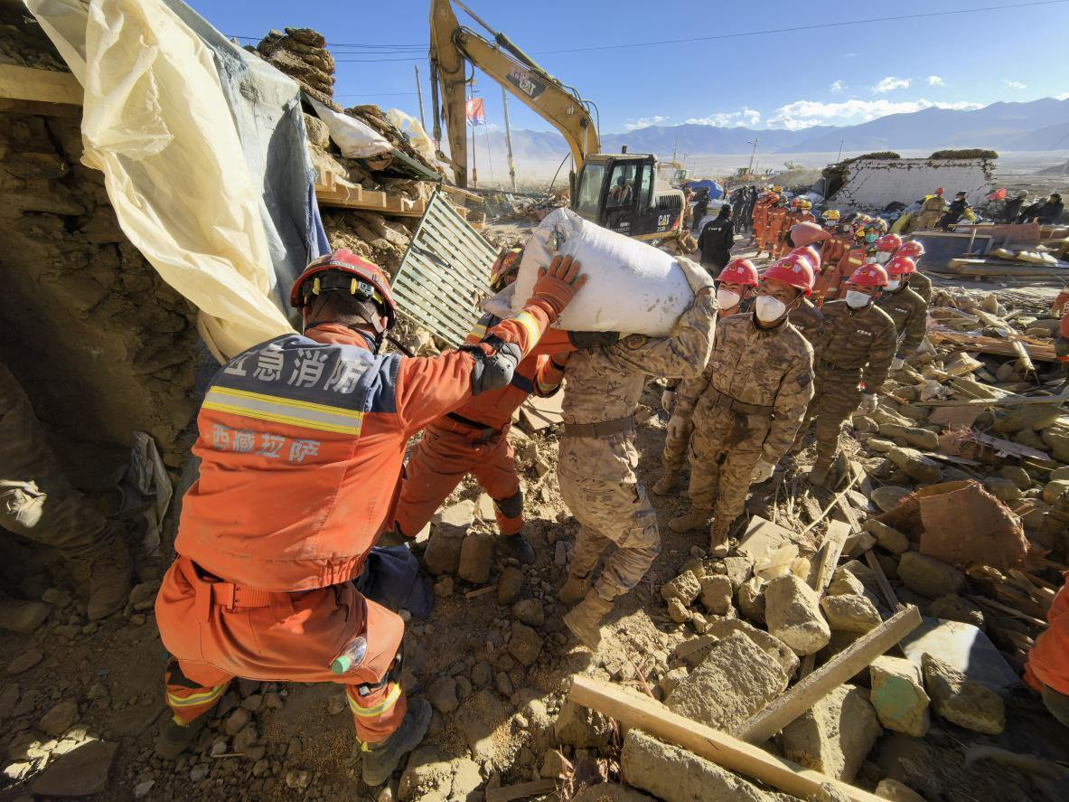 1月11日，定日縣長(zhǎng)所鄉(xiāng)古榮村，應(yīng)急消防等救援人員排隊(duì)接力搶運(yùn)掩埋在倒塌房屋下的群眾財(cái)物。人民日?qǐng)?bào)記者楊翹楚攝