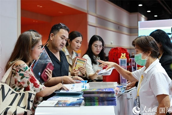 外國(guó)觀眾在中國(guó)展臺(tái)仔細(xì)閱讀赴華旅游介紹，向工作人員咨詢關(guān)于中國(guó)美食和景點(diǎn)的詳細(xì)信息。人民網(wǎng)記者 白元琪攝