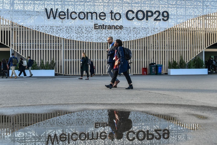 2024年11月15日，在阿塞拜疆首都巴庫(kù)，人們經(jīng)過(guò)聯(lián)合國(guó)氣候變化巴庫(kù)大會(huì)的會(huì)場(chǎng)。新華社記者 曹陽(yáng) 攝