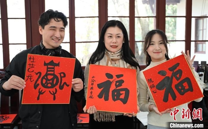 1月20日，外籍留學生和西泠印社社員李硯(中)展示各自創(chuàng)作的福貼。當日，來自巴西、馬來西亞、加納、哈薩克斯坦的外籍留學生在浙江杭州西泠印社體驗福貼、春聯(lián)和篆刻，感受古老的中國傳統(tǒng)文化。中新社記者 王剛 攝