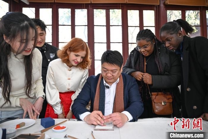 1月20日，篆刻家王臻向外籍留學生展示篆刻印章。當日，來自巴西、馬來西亞、加納、哈薩克斯坦的外籍留學生在浙江杭州西泠印社體驗福貼、春聯(lián)和篆刻，感受古老的中國傳統(tǒng)文化。中新社記者 王剛 攝