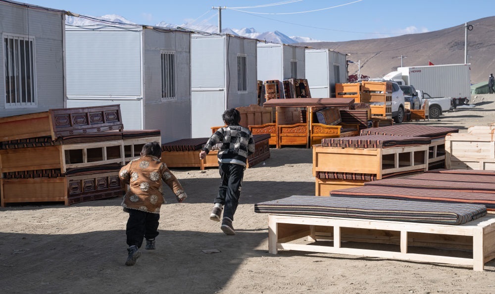 2025年1月13日，在定日縣嘎旦村，兩個(gè)孩子在剛運(yùn)來(lái)的兩排藏床間奔跑。新華社記者丁增尼達(dá) 攝