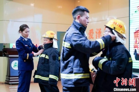 圖為學生們現(xiàn)場穿戴消防頭盔和戰(zhàn)斗服。中新社記者 趙宇航 攝
