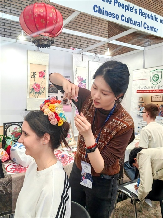 展覽正值羅馬尼亞迎春花節(jié)，國際中文教師志愿者潘婧穎向游客們介紹了國家非物質(zhì)文化遺產(chǎn)——福建泉州的簪花文化。布加勒斯特大學(xué)孔子學(xué)院供圖。