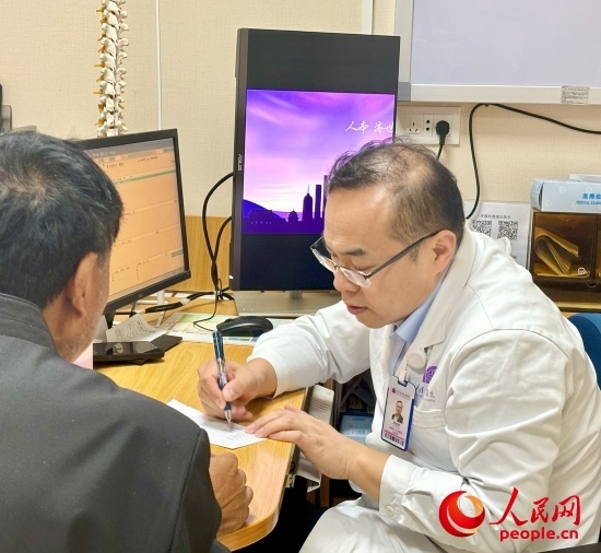 路桂軍接診時(shí)為患者寫下用藥提示。人民網(wǎng)記者 金慧慧攝