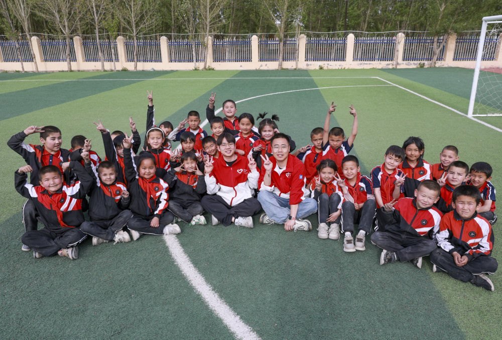 4月23日，在新疆克州阿圖什市哈拉峻鄉(xiāng)謝依特小學(xué)，支教教師王俊文（中左）、李軻凡（中右）和學(xué)生在一起。