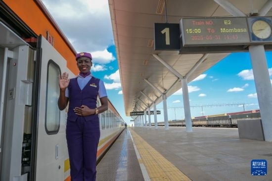 5月31日，在蒙內(nèi)鐵路內(nèi)羅畢站，一名乘務(wù)員在即將開往蒙巴薩的E2次列車旁等候乘客。新華社記者 楊光 攝